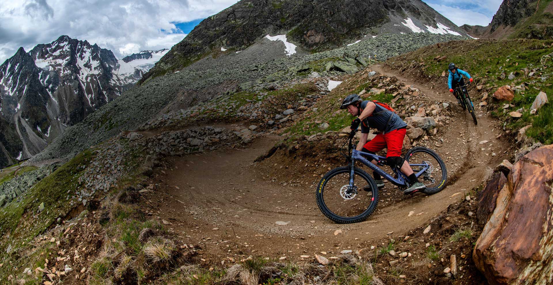 Zwei Mountainbikefahrer fahren mit ihren MTB bergab über einen steinigen Weg.
